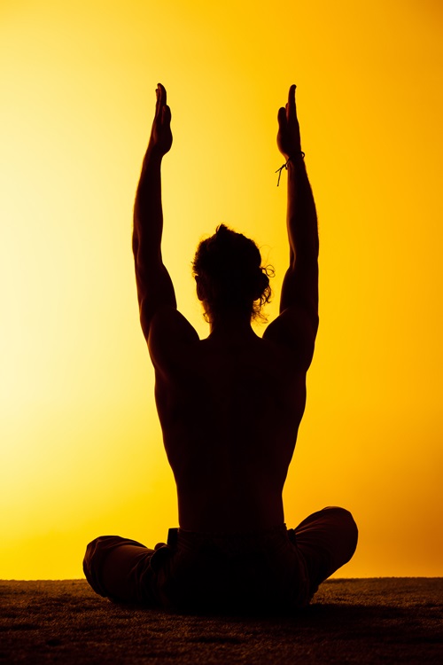 The silhouette of man practicing yoga in the sunset light
